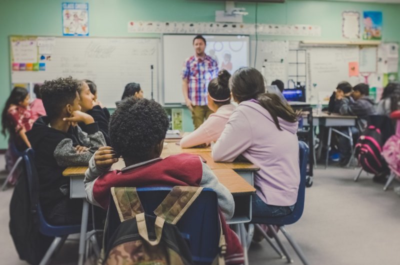 Niños y niñas atienden la explicación de su profesor en un aula